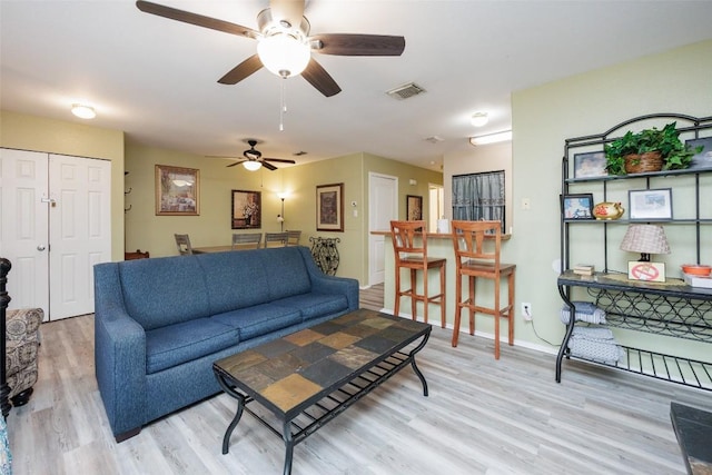 living area featuring light wood finished floors, visible vents, baseboards, and ceiling fan