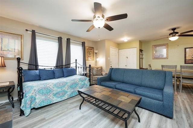living area featuring ceiling fan, baseboards, and wood finished floors
