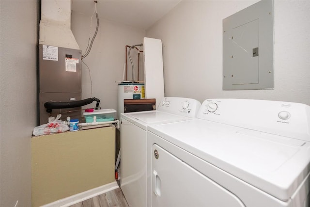 washroom with washing machine and clothes dryer, laundry area, electric panel, and wood finished floors