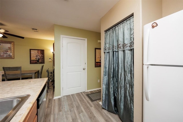 kitchen featuring a sink, freestanding refrigerator, visible vents, ceiling fan, and light wood-style flooring