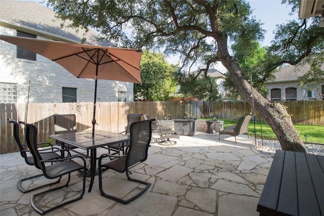 view of patio with an outdoor fire pit, outdoor dining area, and a fenced backyard