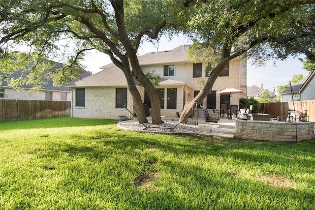 back of property with stone siding, a patio, a lawn, a shingled roof, and a fenced backyard