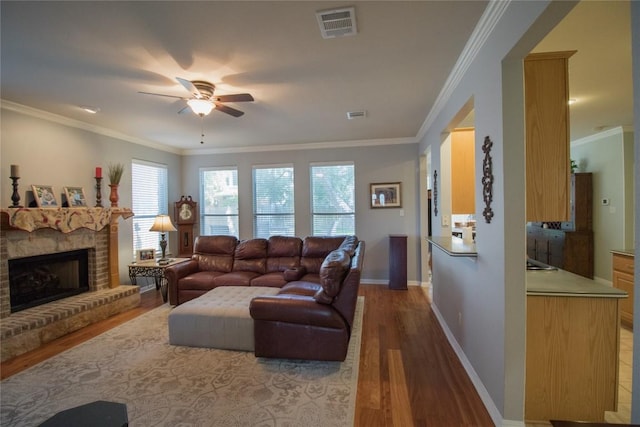living room with a ceiling fan, baseboards, visible vents, wood finished floors, and a fireplace