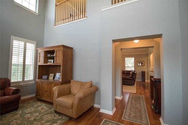 sitting room with a towering ceiling, baseboards, and wood finished floors