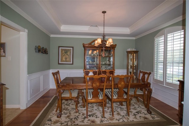 dining room featuring an inviting chandelier, a wealth of natural light, wood finished floors, and a raised ceiling