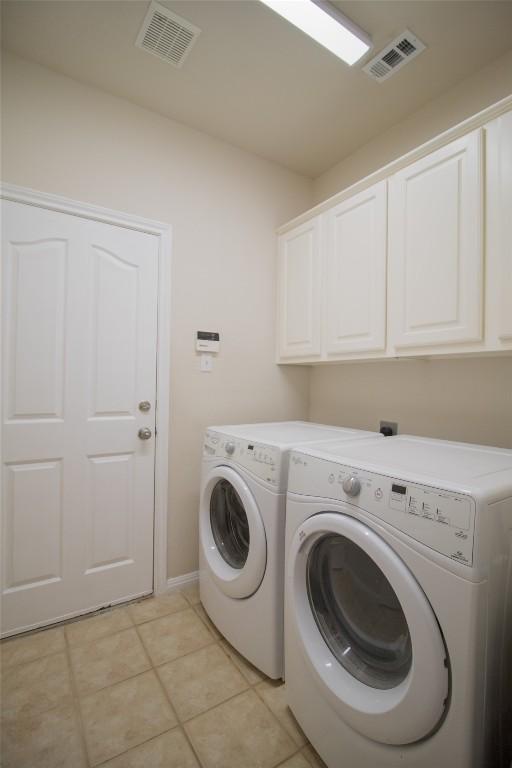 washroom with cabinet space, washing machine and clothes dryer, light tile patterned floors, and visible vents