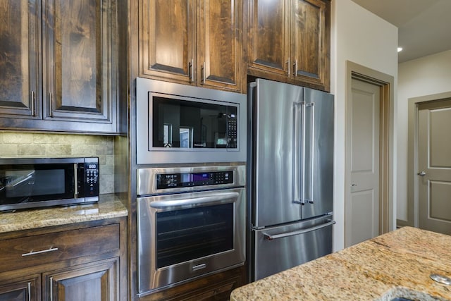 600 Mountain Dew Rd, Horseshoe Bay, TX 78657 - kitchen with dark brown cabinetry, stainless steel appliances, light stone countertops, and backsplash