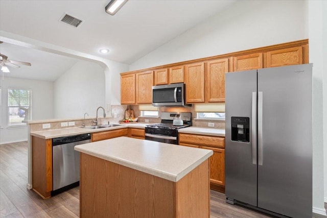 kitchen featuring a sink, wood finished floors, visible vents, vaulted ceiling, and appliances with stainless steel finishes