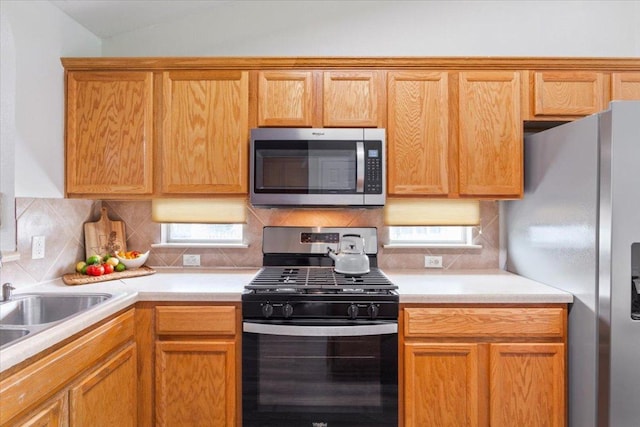 kitchen featuring a sink, lofted ceiling, stainless steel appliances, decorative backsplash, and light countertops