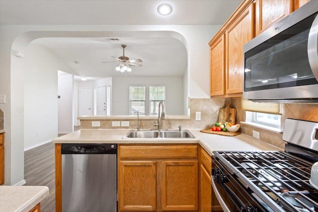 kitchen featuring a peninsula, appliances with stainless steel finishes, arched walkways, and a sink