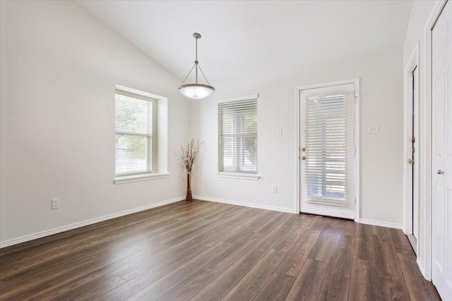 empty room with dark wood-style flooring, lofted ceiling, and baseboards