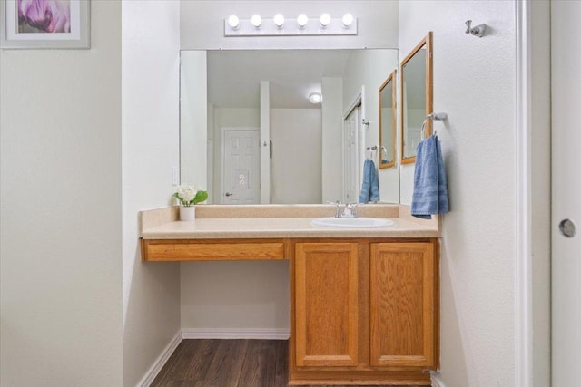 bathroom featuring baseboards, wood finished floors, and vanity