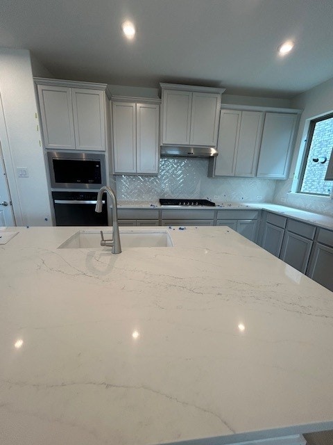 565 Raleigh Dr, Georgetown, TX 78633 - kitchen featuring a sink, light stone counters, stainless steel appliances, gray cabinetry, and backsplash