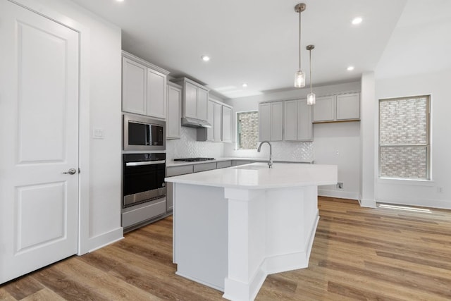 565 Raleigh Dr, Georgetown, TX 78633 - kitchen featuring stainless steel appliances, decorative backsplash, a kitchen island with sink, light countertops, and hanging light fixtures