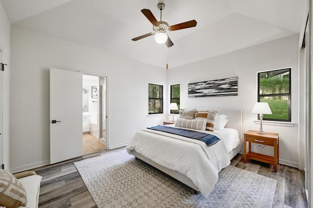 bedroom with multiple windows, connected bathroom, and wood finished floors