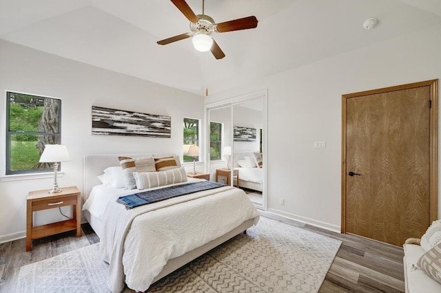 bedroom featuring baseboards, a ceiling fan, multiple windows, and wood finished floors