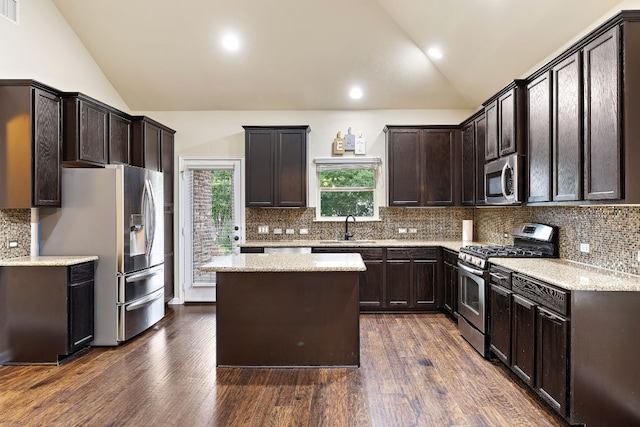kitchen featuring a sink, lofted ceiling, dark brown cabinetry, decorative backsplash, and appliances with stainless steel finishes