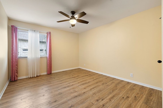 empty room with a ceiling fan, baseboards, and wood finished floors