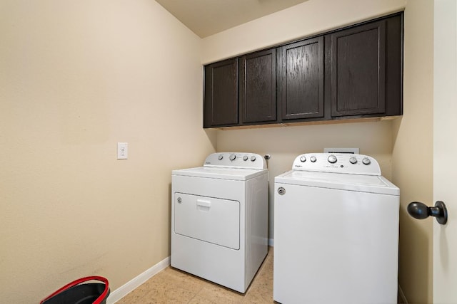 clothes washing area featuring washing machine and clothes dryer, cabinet space, and baseboards