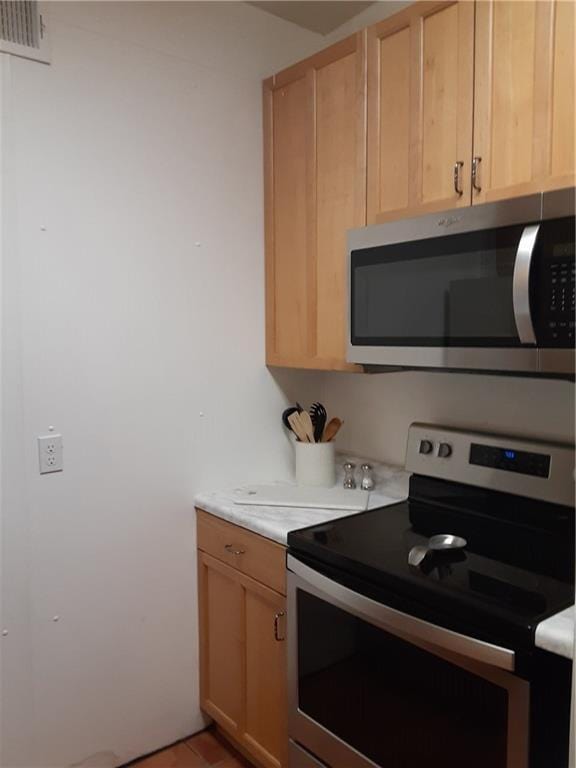 kitchen with light brown cabinetry, light countertops, visible vents, and appliances with stainless steel finishes