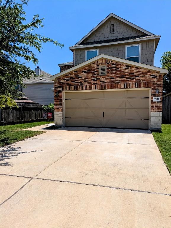 7617 Rio Pass, Austin, TX 78724 - view of front facade featuring stone siding, concrete driveway, an attached garage, and brick siding