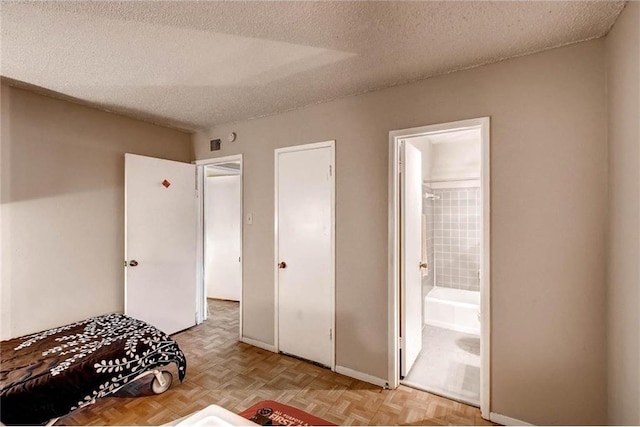 803 W 28th St Unit 105, Austin, TX 78705 - bedroom featuring a textured ceiling, ensuite bathroom, and baseboards