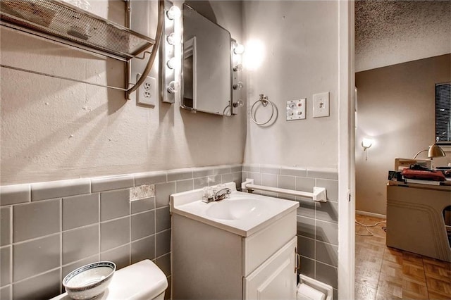 803 W 28th St Unit 105, Austin, TX 78705 - half bathroom featuring toilet, vanity, tile walls, and a wainscoted wall