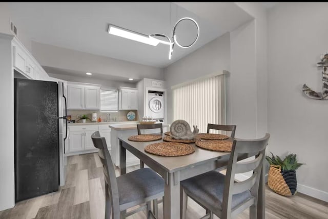 102 W Corral St Unit 2, South Padre Island, TX 78597 - dining area featuring stacked washer / dryer, baseboards, visible vents, light wood-style flooring, and a notable chandelier