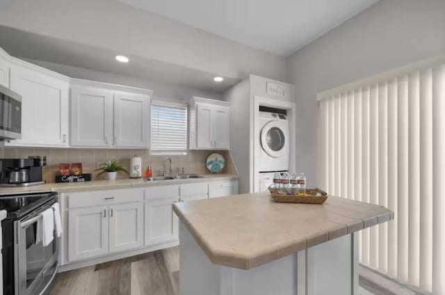 102 W Corral St Unit 2, South Padre Island, TX 78597 - kitchen featuring stacked washer / dryer, a sink, light wood-type flooring, white cabinetry, and appliances with stainless steel finishes