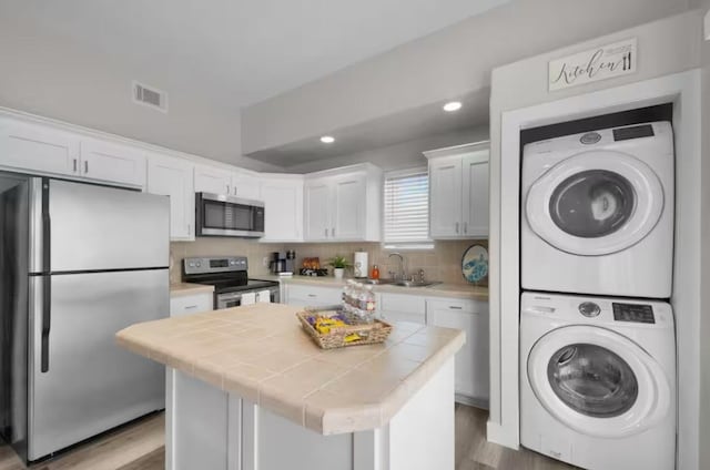 102 W Corral St Unit 2, South Padre Island, TX 78597 - washroom with visible vents, a sink, wood finished floors, laundry area, and stacked washer / drying machine