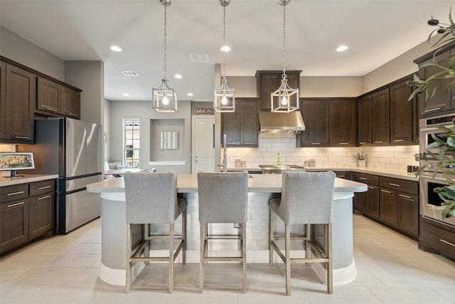 1300 Morning Moon Cir, Austin, TX 78732 - kitchen featuring light countertops, dark brown cabinets, backsplash, a kitchen breakfast bar, and recessed lighting
