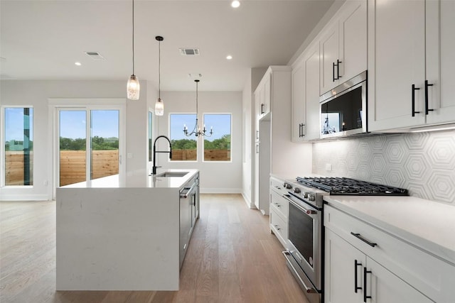 6309 Friendswood Dr, Austin, TX 78723 - kitchen featuring appliances with stainless steel finishes, a chandelier, tasteful backsplash, light wood-style floors, and recessed lighting