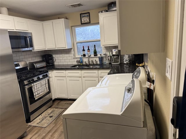 211 Murphy St, Taylor, TX 76574 - kitchen with stainless steel appliances, a sink, washing machine and dryer, decorative backsplash, and wood finished floors