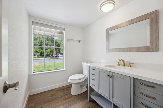 bathroom with toilet, baseboards, vanity, and wood finished floors