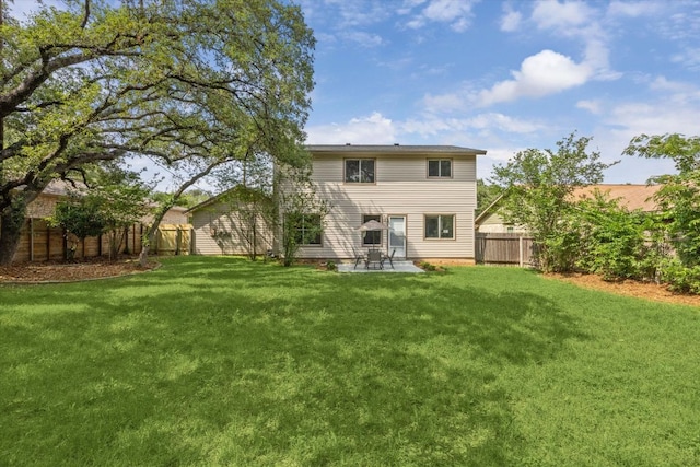 rear view of property featuring a yard, a patio, and a fenced backyard