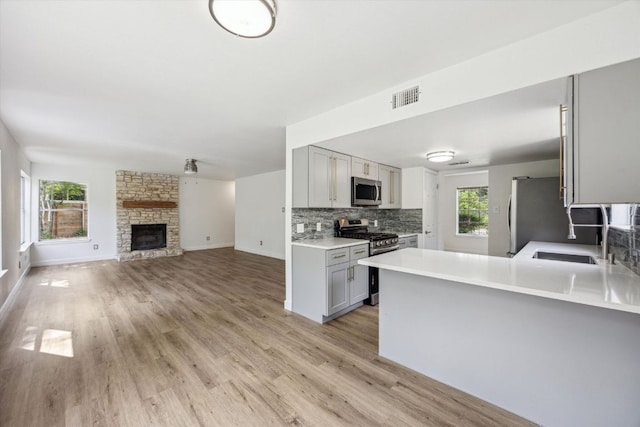 kitchen with light wood finished floors, gray cabinets, visible vents, appliances with stainless steel finishes, and decorative backsplash