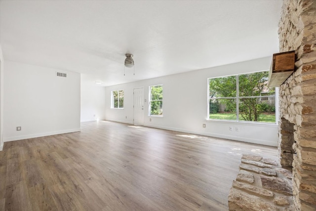 unfurnished living room with baseboards, ceiling fan, visible vents, and wood finished floors