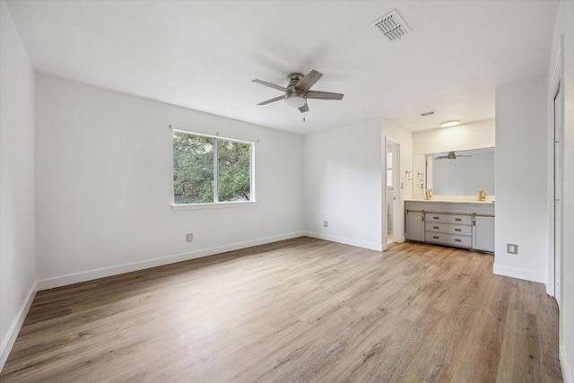 unfurnished bedroom featuring connected bathroom, wood finished floors, visible vents, baseboards, and ceiling fan