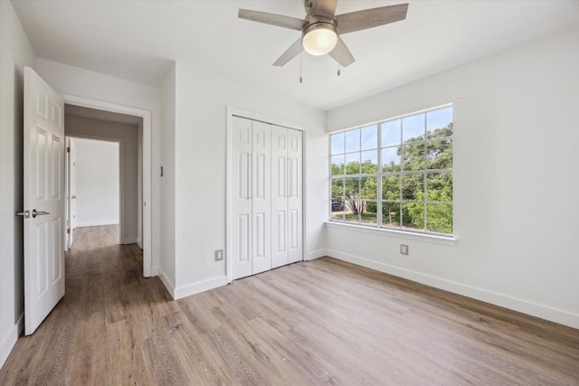 unfurnished bedroom featuring baseboards, light wood finished floors, a closet, and a ceiling fan