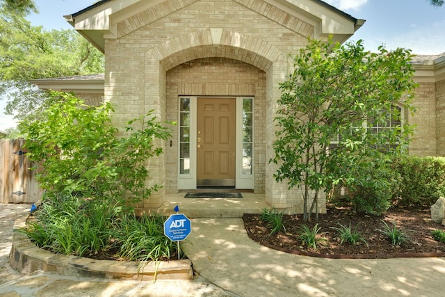 property entrance featuring brick siding and fence