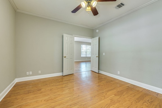 empty room with a ceiling fan, crown molding, baseboards, and light wood-type flooring