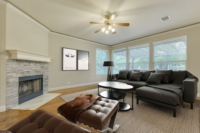 living room featuring ornamental molding, a ceiling fan, baseboards, wood finished floors, and a tiled fireplace