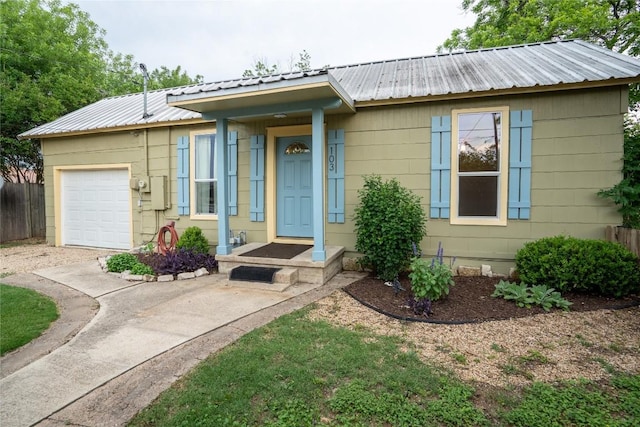 ranch-style house featuring an attached garage, concrete driveway, and metal roof