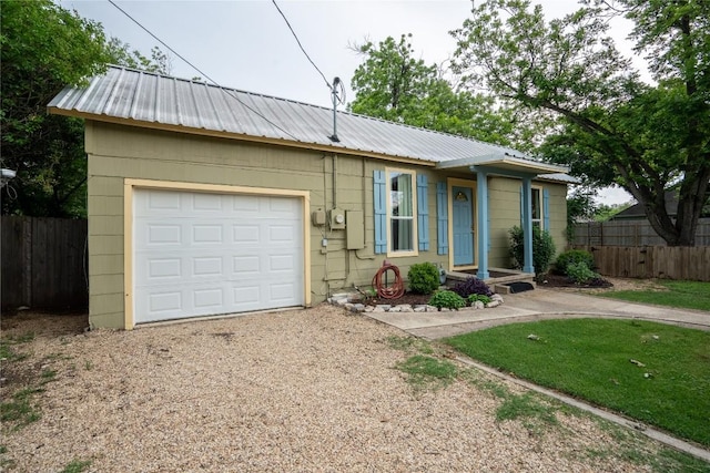 single story home with gravel driveway, metal roof, and fence