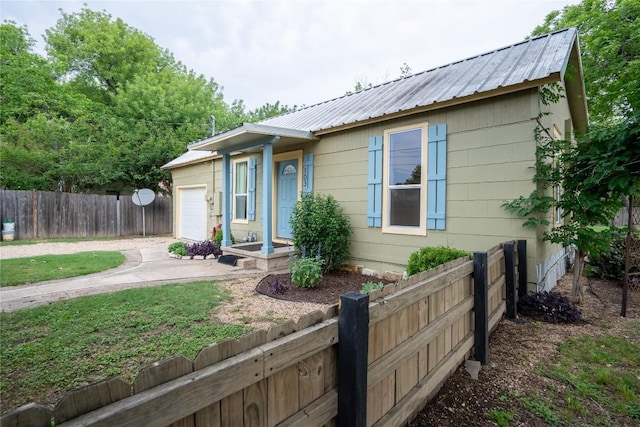single story home with an attached garage, driveway, fence, and metal roof