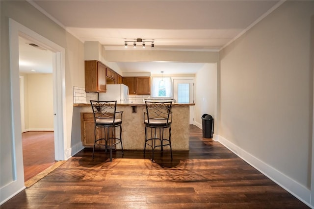 kitchen with a breakfast bar area, brown cabinets, freestanding refrigerator, dark wood finished floors, and visible vents