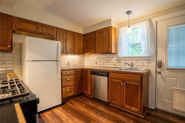kitchen featuring freestanding refrigerator, stainless steel dishwasher, a sink, backsplash, and brown cabinets