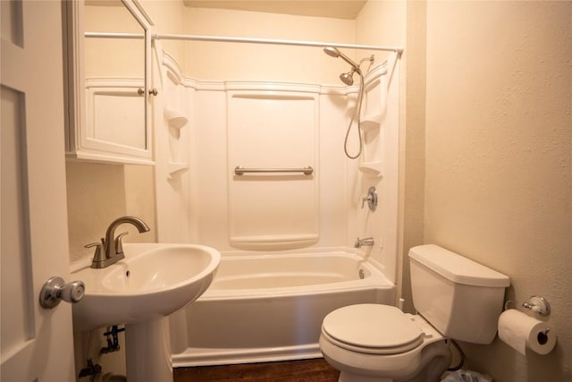 bathroom with toilet, tub / shower combination, wood finished floors, a sink, and a textured wall