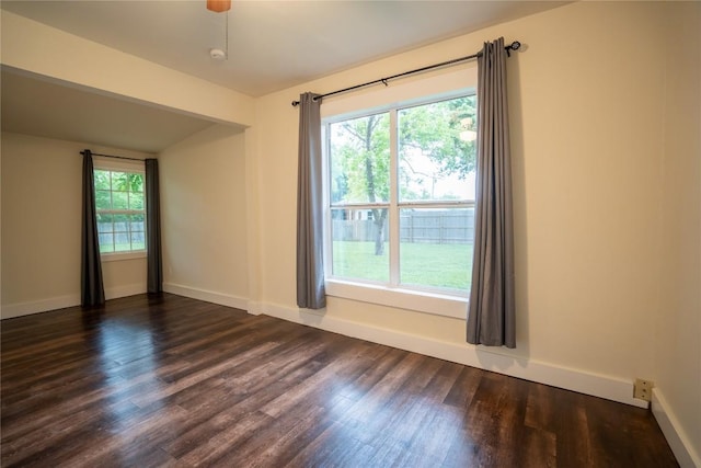 empty room featuring dark wood-style flooring, baseboards, and a healthy amount of sunlight