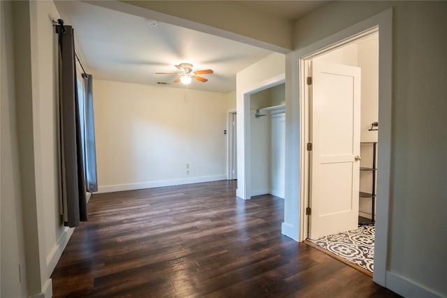 spare room with a ceiling fan, dark wood-style flooring, and baseboards